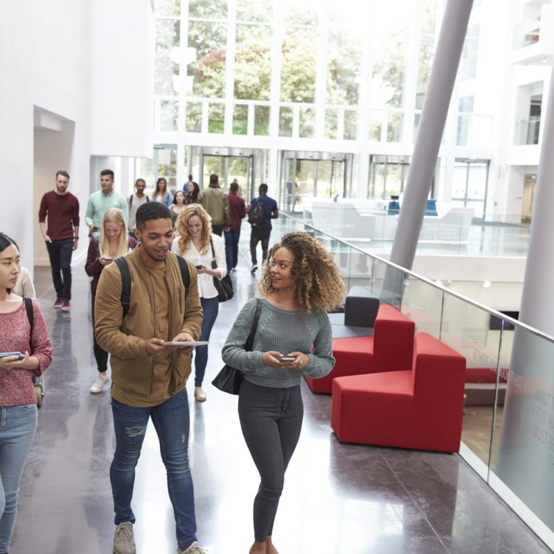 Students walk and talk using mobile devices in university